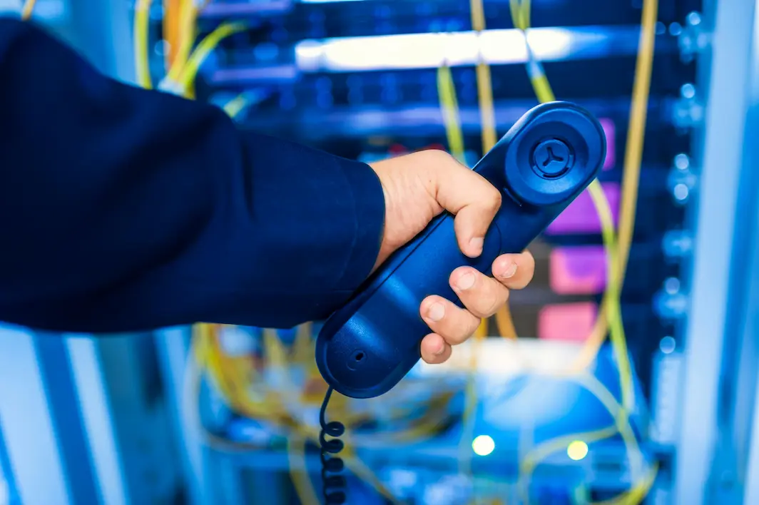 Someone holding a phone receiver in a server room